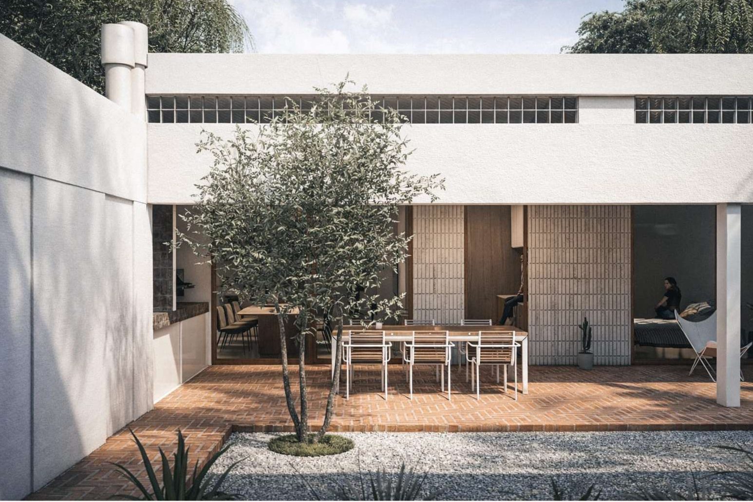 Patio de ladrillo de Casa Ballod, con olivo y galería